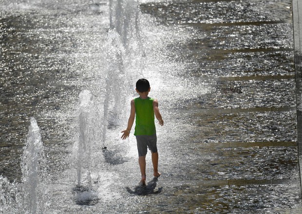 Un bambino gioca nelle fontane di piazza De Ferrari, a Genova © ANSA