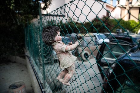 Una bambola incastrata nella rete di un'area per i giochi dei bambini ricoperta del fango dell'alluvione di un mese fa, Faenza (Ravenna)