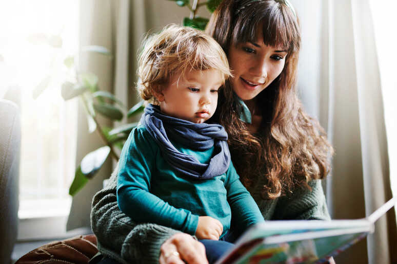 una mamma legge un libro al figlio foto iStock. - RIPRODUZIONE RISERVATA