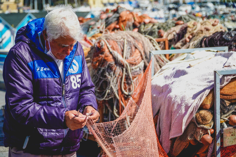 Coronavirus: pescatore al lavoro sul lungomare di Napoli - RIPRODUZIONE RISERVATA