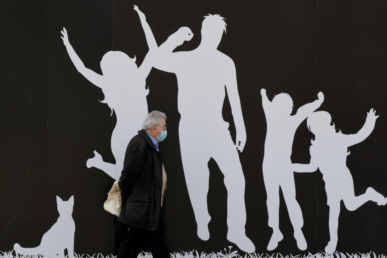 Una persona con il volto coperto da una mascherina cammina davanti un murales, Milano, 24 febbraio  2021.ANSA/DANIEL DAL ZENNARO - RIPRODUZIONE RISERVATA