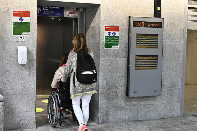 Un disabile accompagnato da una persona in una stazione - RIPRODUZIONE RISERVATA