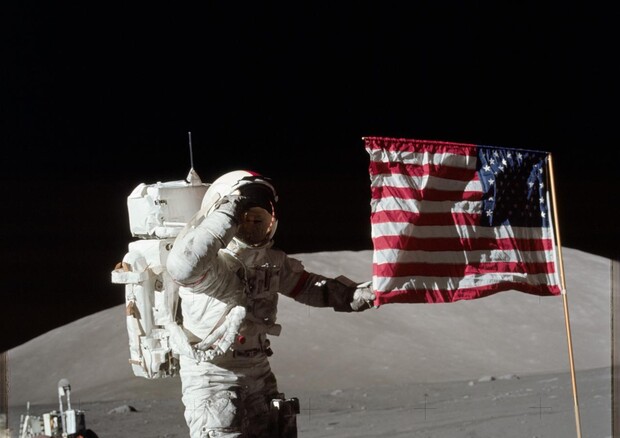 Eugene Cernan, comandante dell'Apollo 17, fotografato accanto alla bandiera americana durante la missione (Fonte: NASA) © Ansa