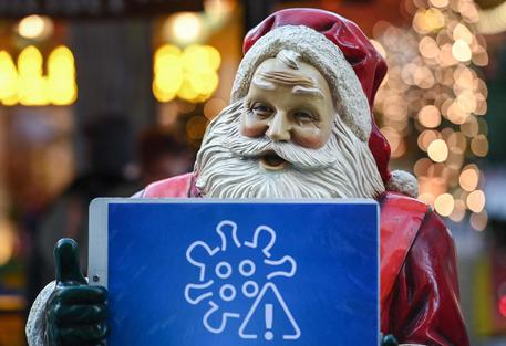 Una statua di Babbo Natale all'ingresso di un mercatino natalizio mostra le avvertenze per evitare la diffusione del Covid © AFP