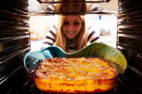 Una donna sforna una tiella di lasagne dal forno foto iStock.