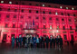 La presidente del Consiglio, Giorgia Meloni, con i ministri davanti a Palazzo Chigi illuminato con luci di colore rosso © ANSA