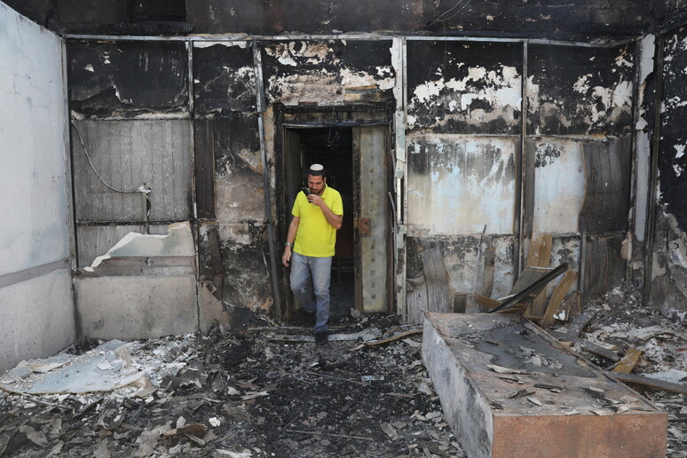 Un israeliano ispeziona una sinagoga devastata da un rogo a Lod © ANSA/EPA