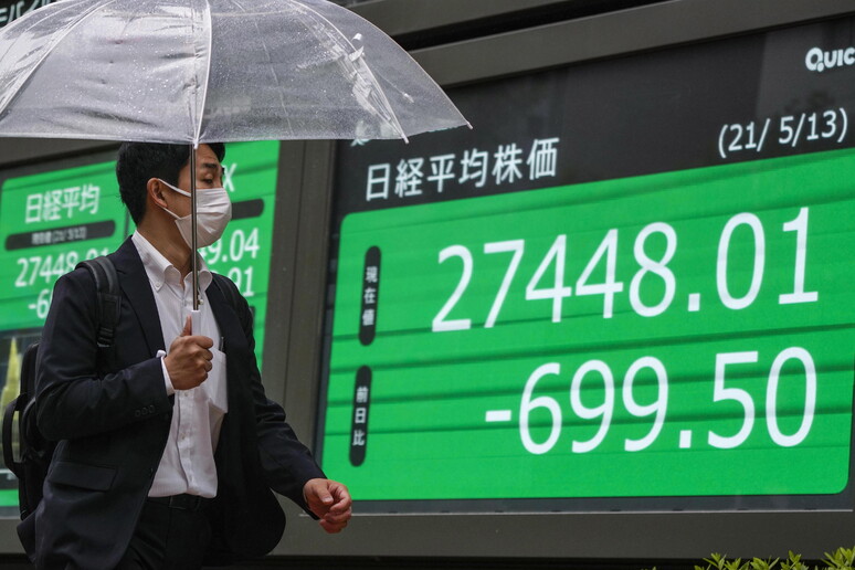 Un passante a Tokyo davanti al monitor che mostra il calo dell 'indice Nikkei © ANSA/EPA