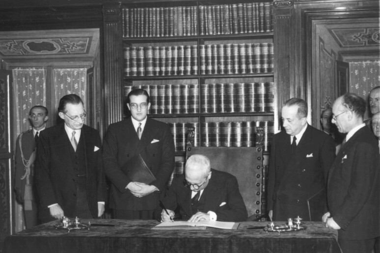Foto da archivio. Il capo provvisorio dello Stato Enrico De Nicola (c), alla presenza di Alcide de Gasperi (s) e Umberto Terracini (primo a destra) firma il testo della Costituzione entrata in vigore l '1 gennaio 1948 - RIPRODUZIONE RISERVATA